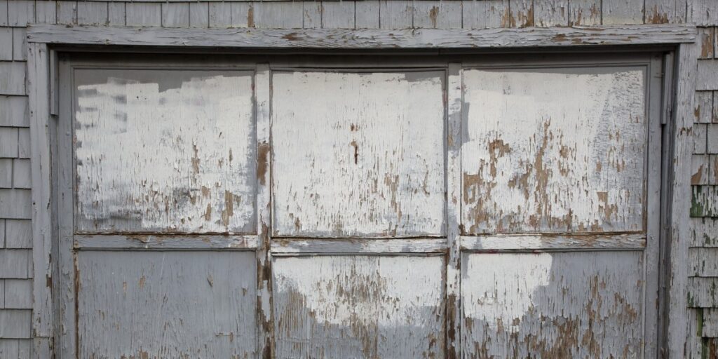 A decaying garage door with chipping white paint.
