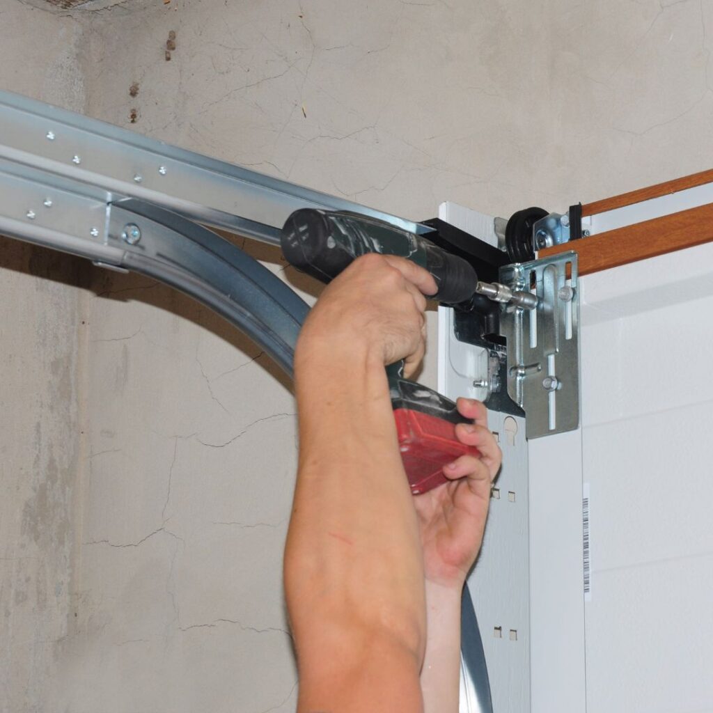 A person tightening loose garage door parts