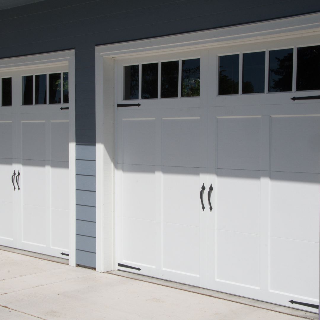 a blue double garage with white barn style garage doors with windows at the top