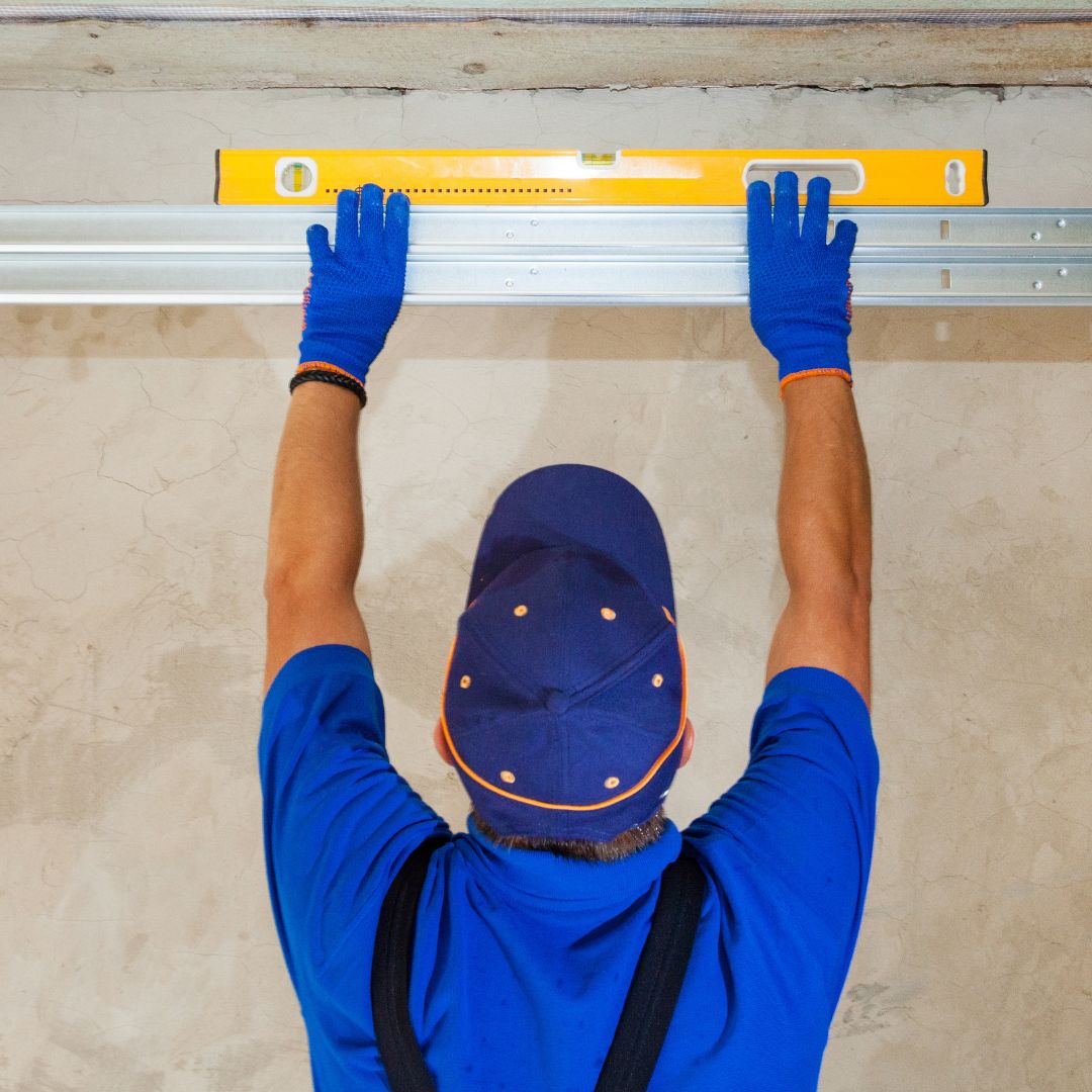a professional garage door installer using a level on a garage track